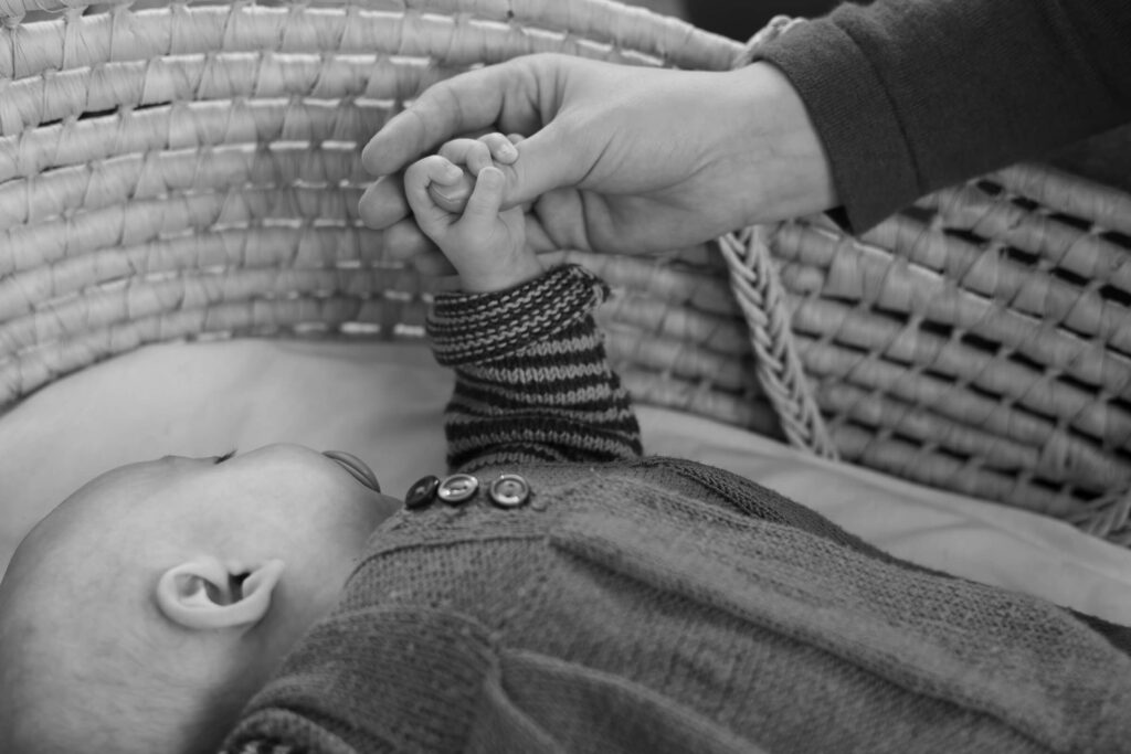 Babyfotos- Baby liegt schlafend im Korb und hält Mamas Hand, Hamburg