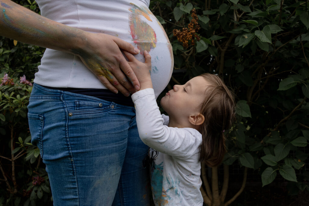 Babybauchfotografie in Hamburg, Kind küsst Bauch der schwangeren Mutter_Babybauchfotografin Hamburg_Schleswig Holstein